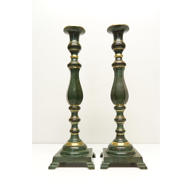 A pair of brass candlesticks with a faux green patina finish. Marked on the bottom with provenance reading Japan.
