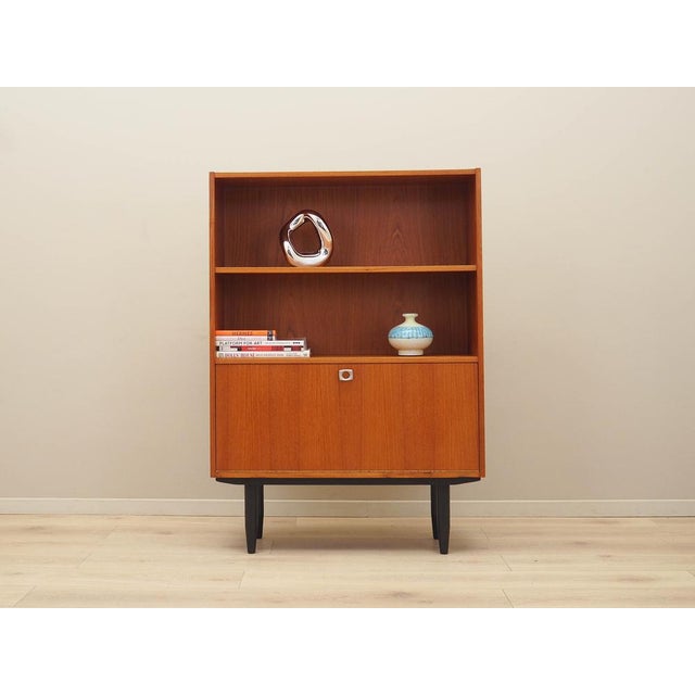 The bookcase was made in the 1960s in Denmark. The structure is covered with teak veneer. The legs are made of solid wood...