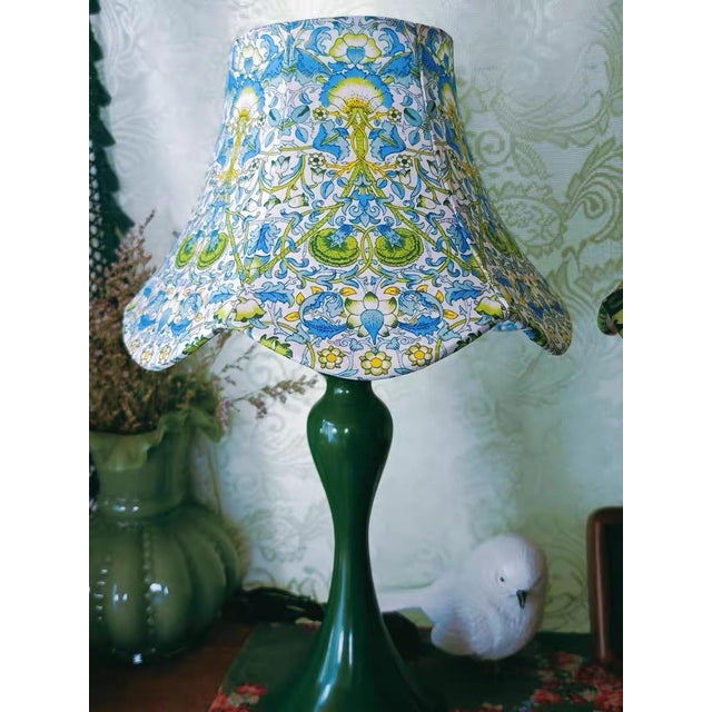 Shade is white-based blue-green floral fabric (intricate plant pattern, wave-edge design), body is glossy dark green...