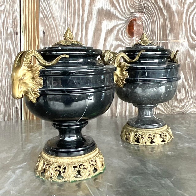 Elevate your decor with this striking pair of vintage urns featuring black marble and brass ram's head motifs. Combining...
