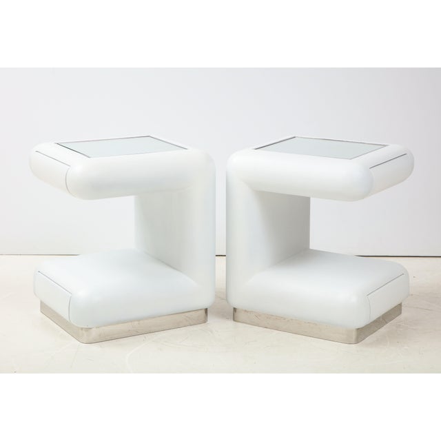 Pair of Ron Seff night stands / End table that are covered in white leather. The tables have mirrored tops framed by a...