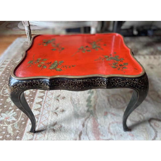 An elegant chinoiserie tray table displaying beautiful colors of ebony and Chinese red with gold filigree accents.