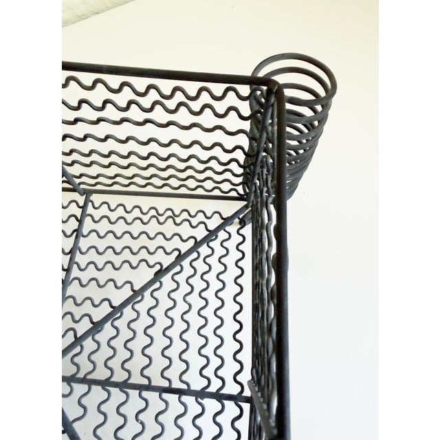 A vintage industrial basket featuring a distinctive wavy wire mesh design with four large spiral coils at the corners....