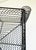 A vintage industrial basket featuring a distinctive wavy wire mesh design with four large spiral coils at the corners....