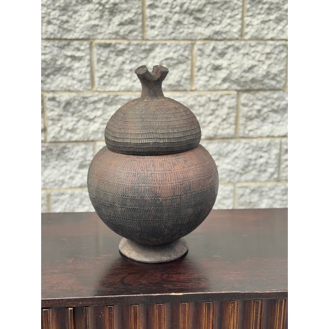 Mid-20th century hand-built terracotta lidded vessel attributed to the Lobi pottery tradition of Burkina Faso. The rounded...