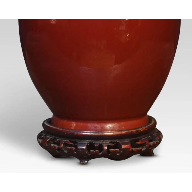 Chinese porcelain monochrome sang-de-boeuf baluster vase lamp, with carved and pierced wood base. Dimensions Height 22.5...