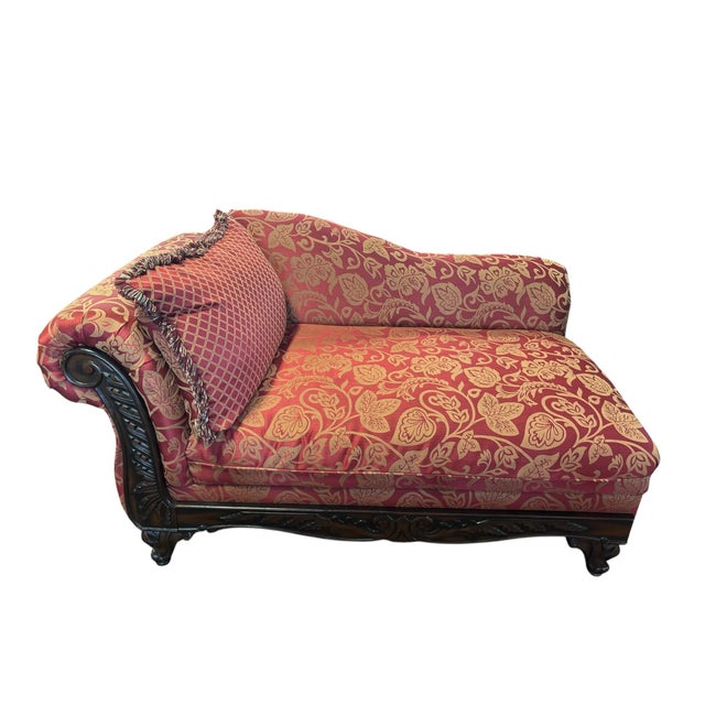 Elegant traditional chaise lounge featuring a richly carved mahogany frame with scrolling arm, acanthus leaf carvings, and...