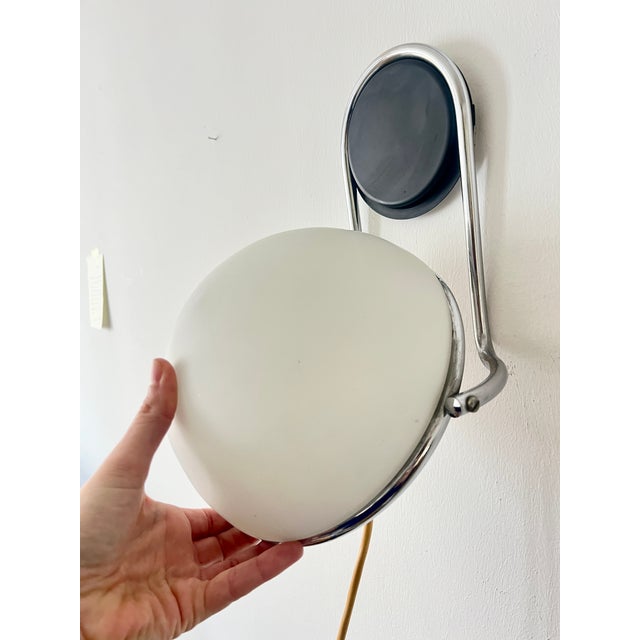 Original vintage Space Age wall lamp manufactured in Italy during the 1970s. The lamp combines chromed metal structure...