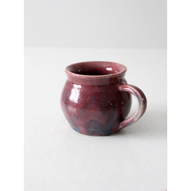 This is a vintage studio pottery mug. Signed by the artist, the handmade mug has a swirling purple and blue glaze.