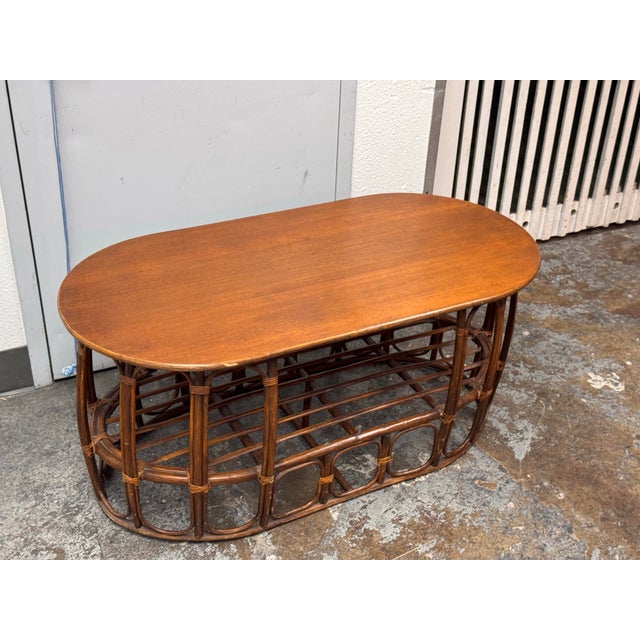 Design Plus Gallery presents a Circa 1970’s Italian Rattan & Wood Coffee Table. This vintage coffee table has an oval wood...