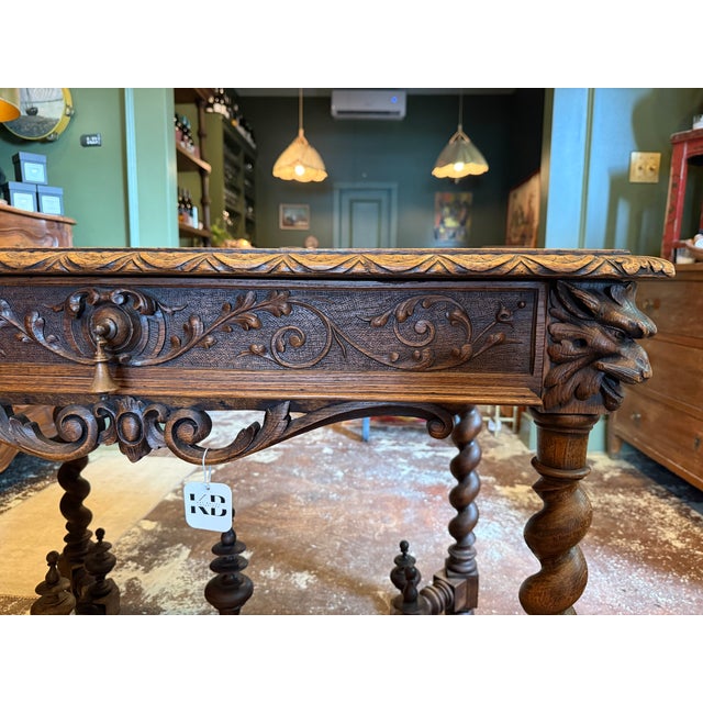 A beautifully carved antique oak table featuring scrolling foliage, barley-twist legs, and a stretcher base. The single...