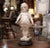 Charming and expressive, this antique plaster sculpture depicts a young girl standing in a playful pose while gently...