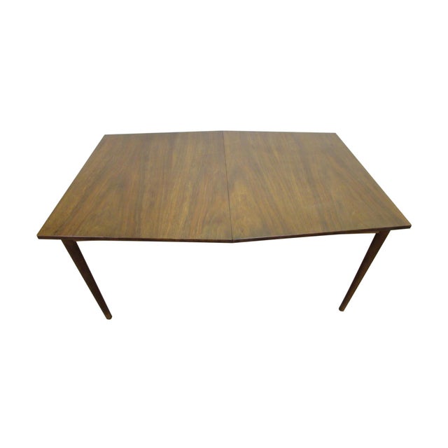 Mid Century Modern wood dining table in medium wood tones. The top is an unusual elongated hexagon shape, with both table...