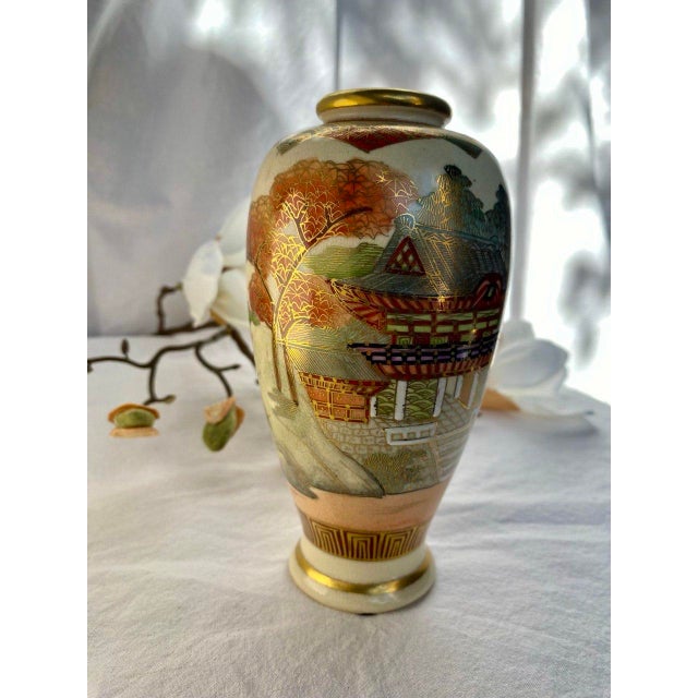 This finely painted Japanese Satsuma vase presents a serene landscape composition rendered in soft enamel tones and...