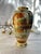 This finely painted Japanese Satsuma vase presents a serene landscape composition rendered in soft enamel tones and...