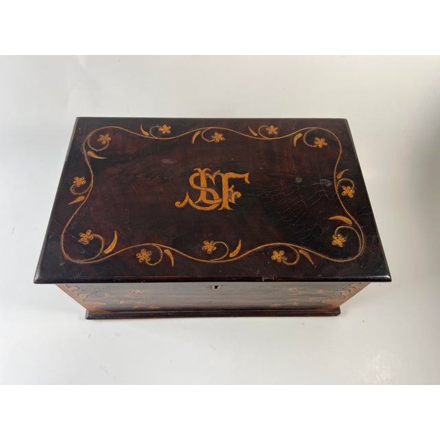 Charming antique wooden box with floral garland scroll inlay, urns at corners and initial inlays atop. 5 1/4" H x 11 1/2"...