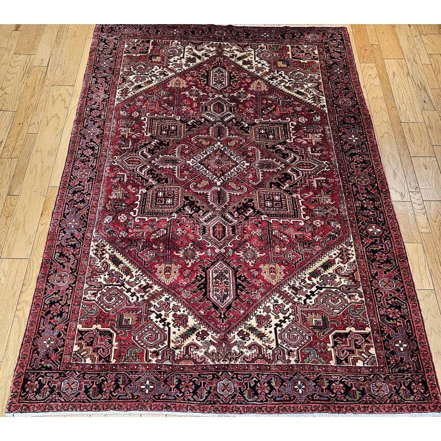 "A room-size Persian Heriz rug from the third quarter of the 20th century featuring a rich brick-red field elegantly...