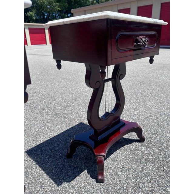 A beautifully matched pair of vintage Kimball end tables featuring genuine white marble tops, elegant lyre-form pedestal...