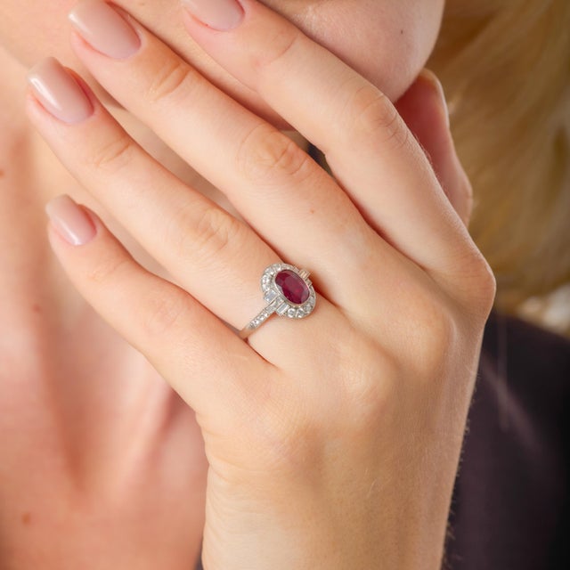 This striking platinum ring is a refined expression of modern luxury centered around a vivid GIA-certified ruby of...