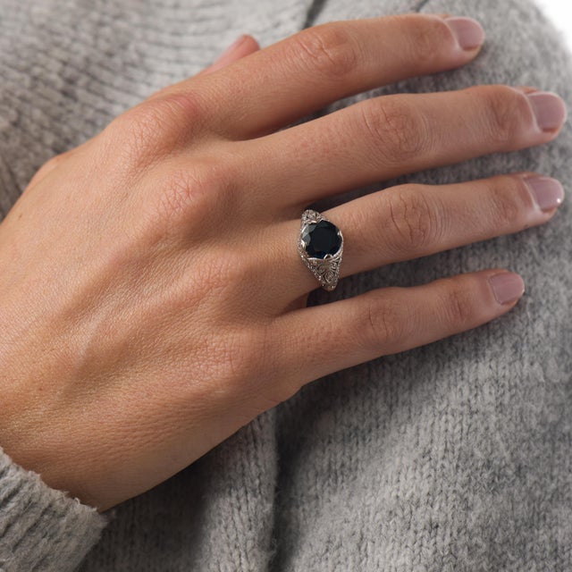 This exquisite Art Deco filigree ring centers on a captivating 2.60 carat round brilliant cut sapphire, certified by GIA...