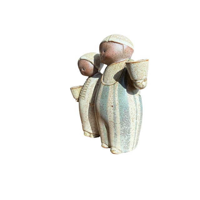 Offering an adorable vintage Japanese stoneware figurine of a peasant couple arm in arm holding pots which functions as a...