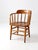 Vintage Early American captain's chair in warm oak, featuring a continuous curved arm, turned spindle back, sculpted crest...