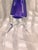 This is a very unusual art glass perfume bottle. The bottle itself is purple and that bottle sits in or on a clear base or...