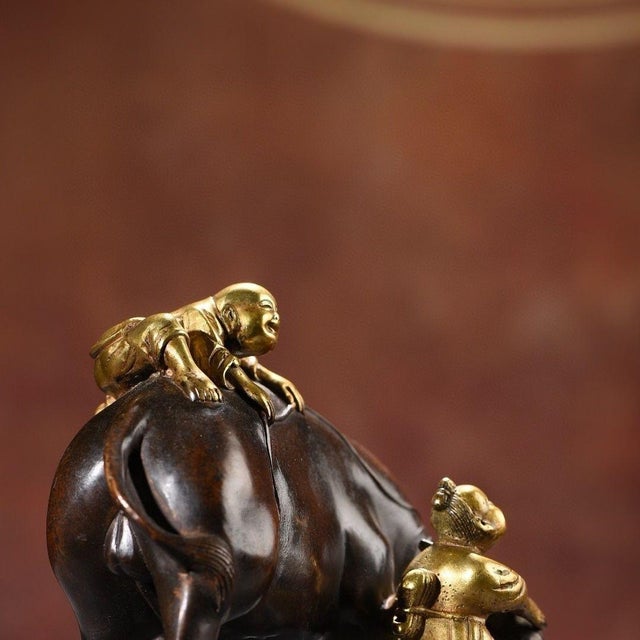 This is a charming vintage Chinese gilt bronze sculpture depicting two young boys interacting with a water buffalo. The...