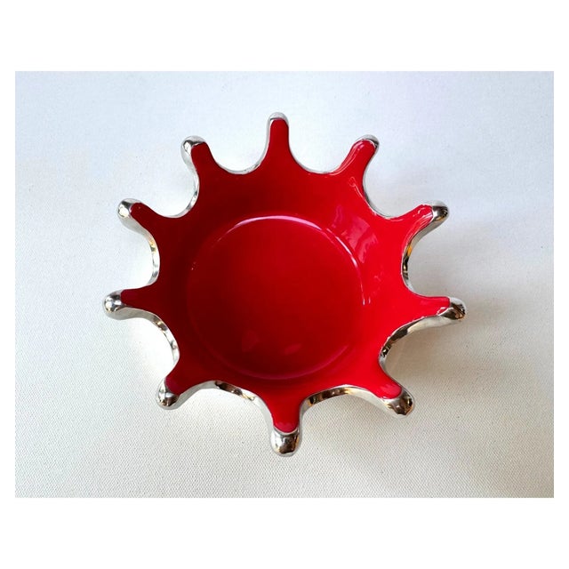 A dramatic Lunares small Splash Bowl in polished sand-cast aluminum with a glossy crimson-red enamel interior. Its crown-...