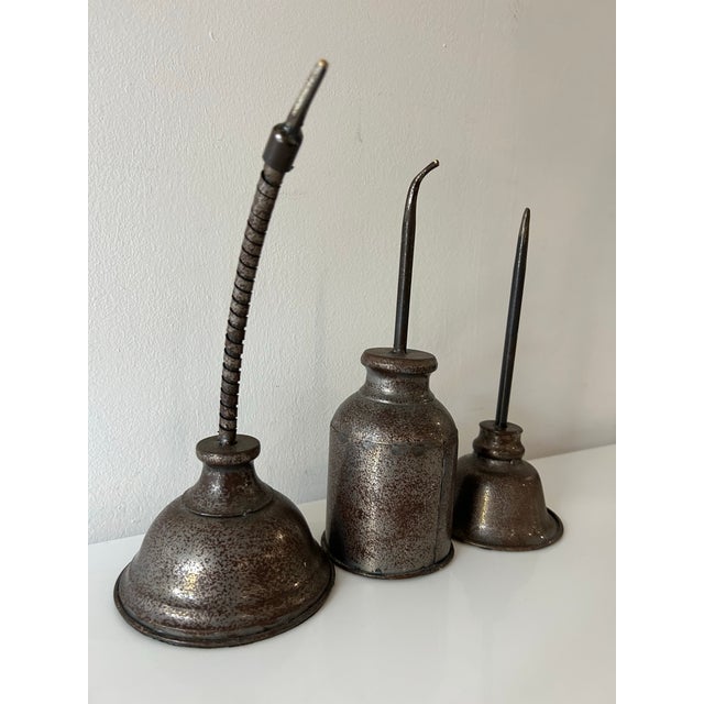 Set of three different shaped faux oil cans by Ballard Designs, item has been discontinued. Rusty chrome finish.