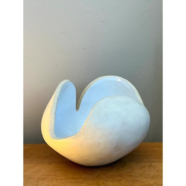 This vintage white ceramic sculptural bowl embodies Mid-Century Modern design with a dynamic, organic form reminiscent of...