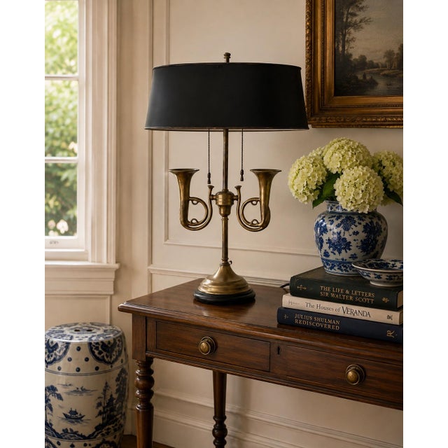 A classic bouillotte lamp rendered in warm brass, distinguished by its sculptural double horn base and clean, tailored...