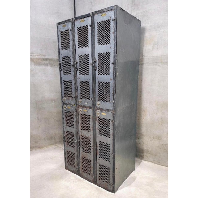 A six-compartment industrial steel locker unit with ventilated perforated doors and numbered brass plaques. A great pieces...