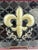 Hand-painted rectangular glass platter featuring a bold fleur-de-lis motif in gold and bronze tones, centered against a...