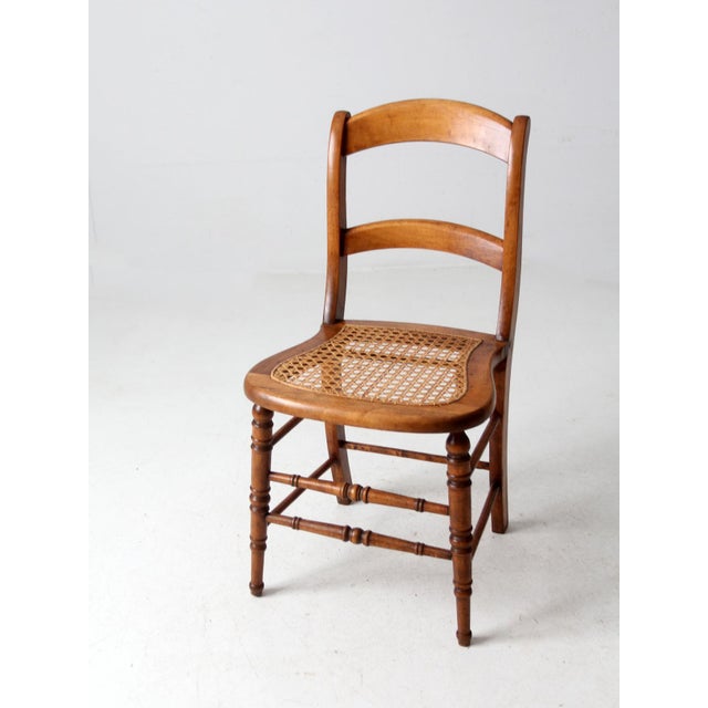 This is an antique American cane seat dining chair circa 1890s - 1920s. The French country style chair features a curving...