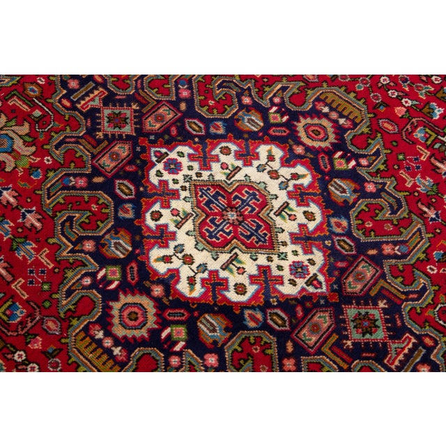 Beautiful vintage Persian Tabriz hand-knotted wool rug with a red color field. This piece has a navy blue frame and...