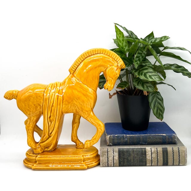 Striking vintage horse figurine crafted in glossy glazed ceramic and finished in a rich mustard yellow tone. The...