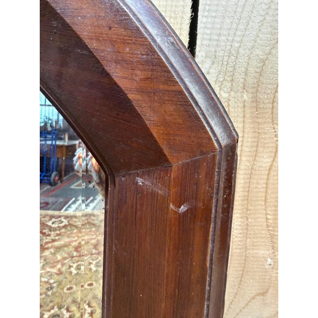 Large octagonal wall mirror with a solid, dark mahogany-stained wood frame and a beveled glass. The frame's corners are...