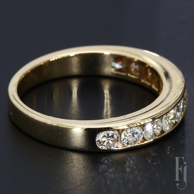 This is an 18k yellow gold and diamond ring brought to a high shine with eleven round brilliant diamonds in a channel...