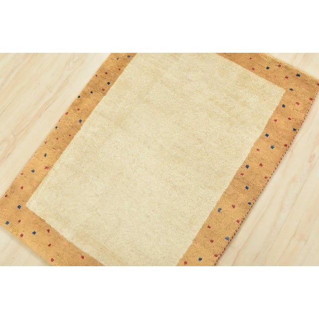 A contemporary Gabbeh rug hand-knotted with an all-wool pile on a cotton foundation. This finely woven area rug features a...