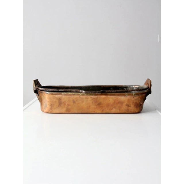 A 19th century antique copper fish pot, or poissonnière, crafted in France. This long, rectangular vessel was...