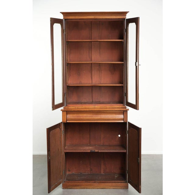 This subtle antique English bookcase/display cabinet from the 19th century, complete with a working key. This antique...