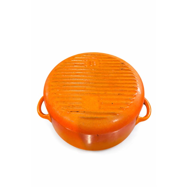 A timeless vintage French enameled cast iron Dutch oven in the iconic flame-orange hue, prized for both its performance...