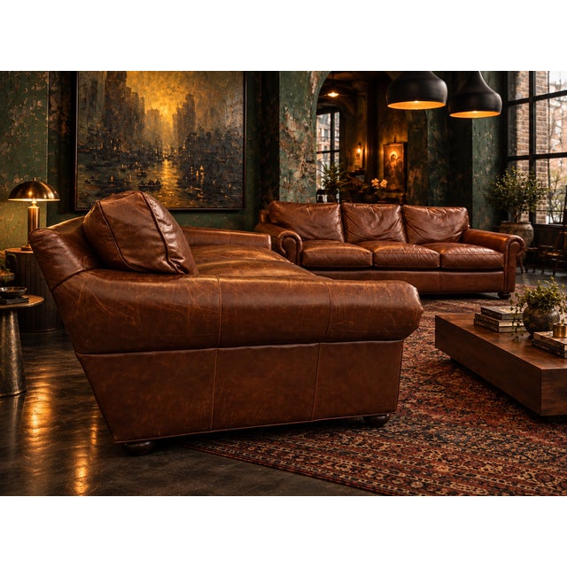 A substantial pair of matching three-seat sofas upholstered in rich cognac brown leather. The set features oversized...