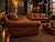 A substantial pair of matching three-seat sofas upholstered in rich cognac brown leather. The set features oversized...