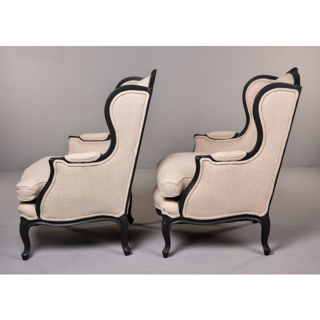 This pair of Louis XV-style wingback chairs features an elegant contrast between their ebonized frames and neutral,...