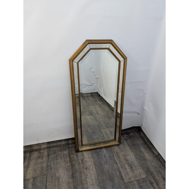 Mirror in a gilded, aged wood frame. The frame has a geometric shape with decorative mirror inserts that emphasize the...