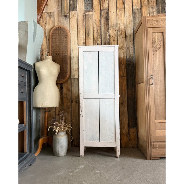 A charming parisian wardrobe. This small cabinet bears the marks of a long and well-lived life: cracked white and pale...