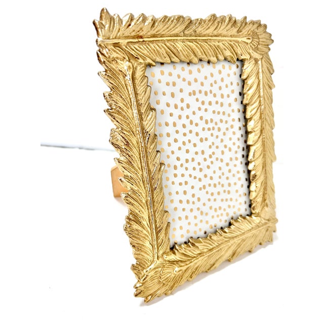 Vintage Hollywood Regency picture frame featuring a sculptural gilt feather motif with rich gold tone and dimensional...