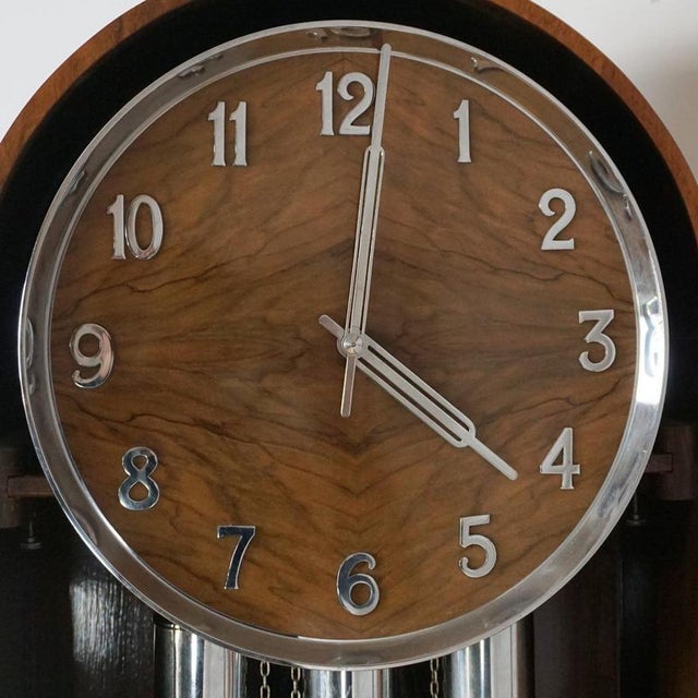 An Art Deco Longcase clock. Burr and figured walnut veneered with eight day movement and quarter hour Westminster chimes....